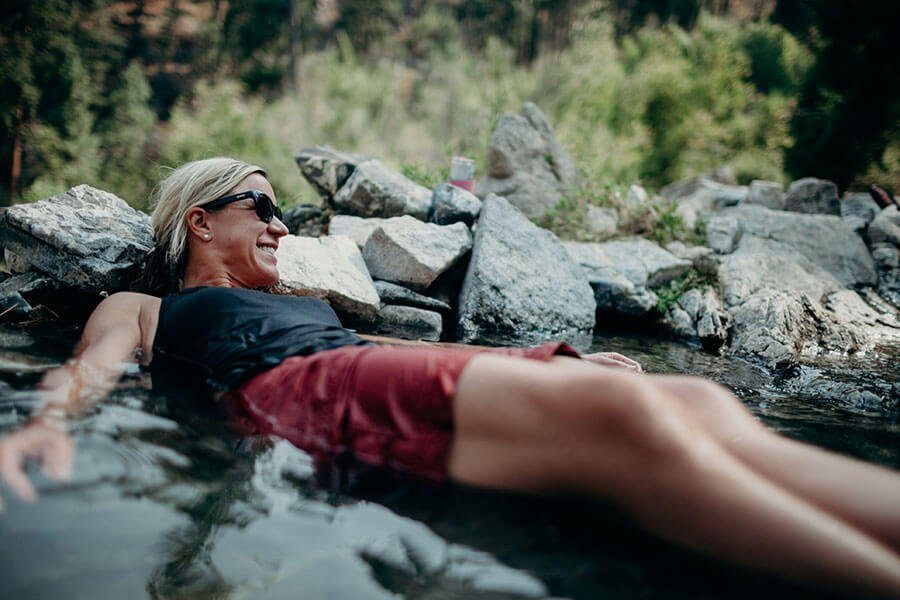 Guest relaxing in a rock-lined hot spring beside the Middle Fork river corridor