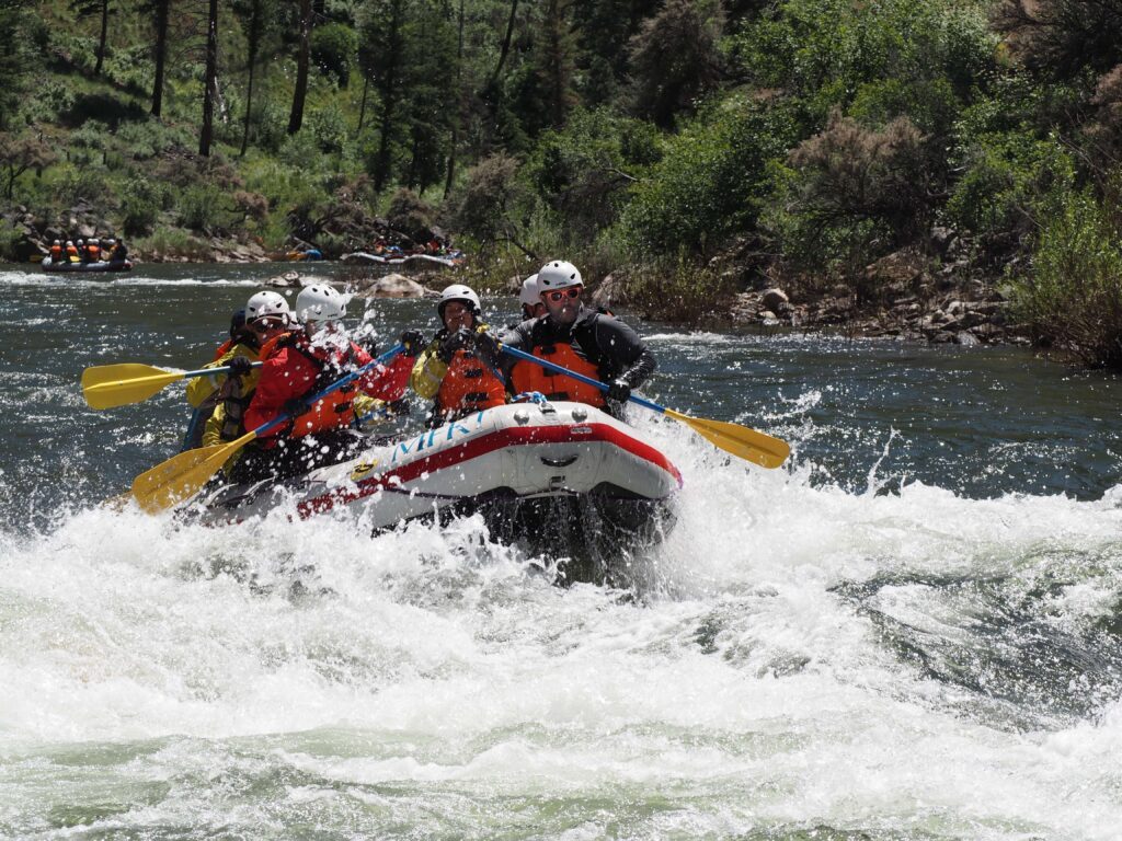 A paddle raft splashes through a Middle Fork rapid with helmeted rafters aboard