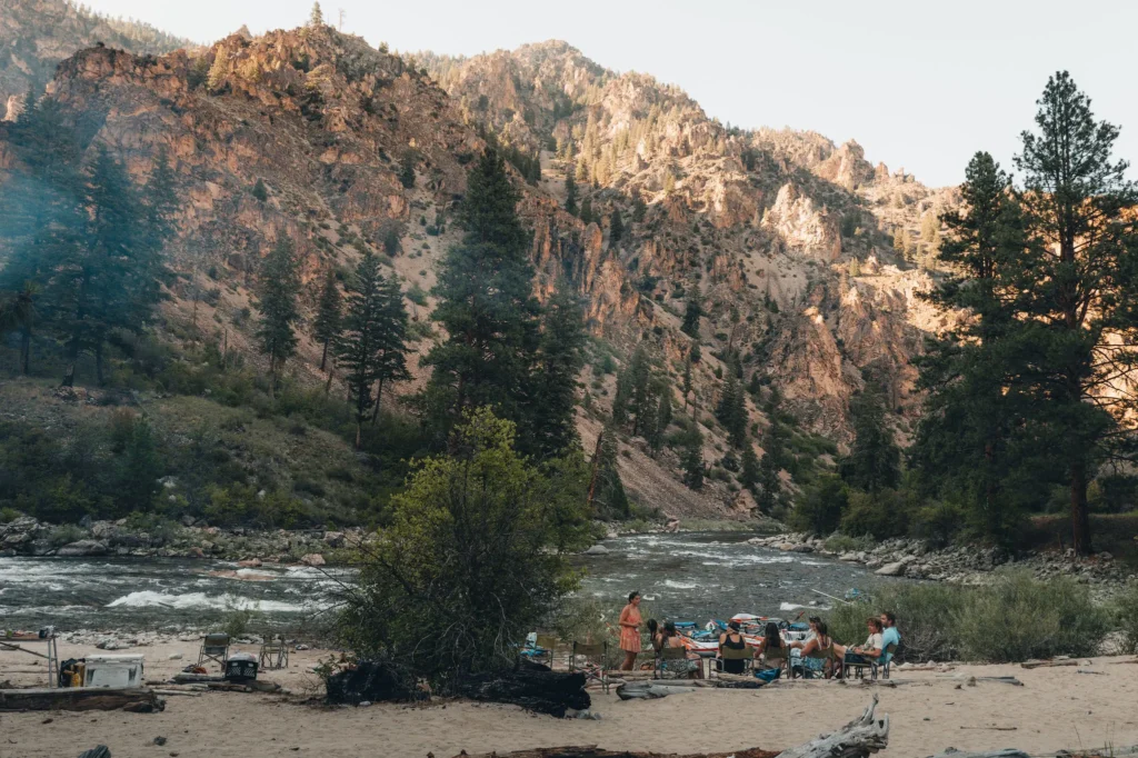 MFRT guests relaxing at a riverside camp beneath canyon walls on the Middle Fork of the Salmon River